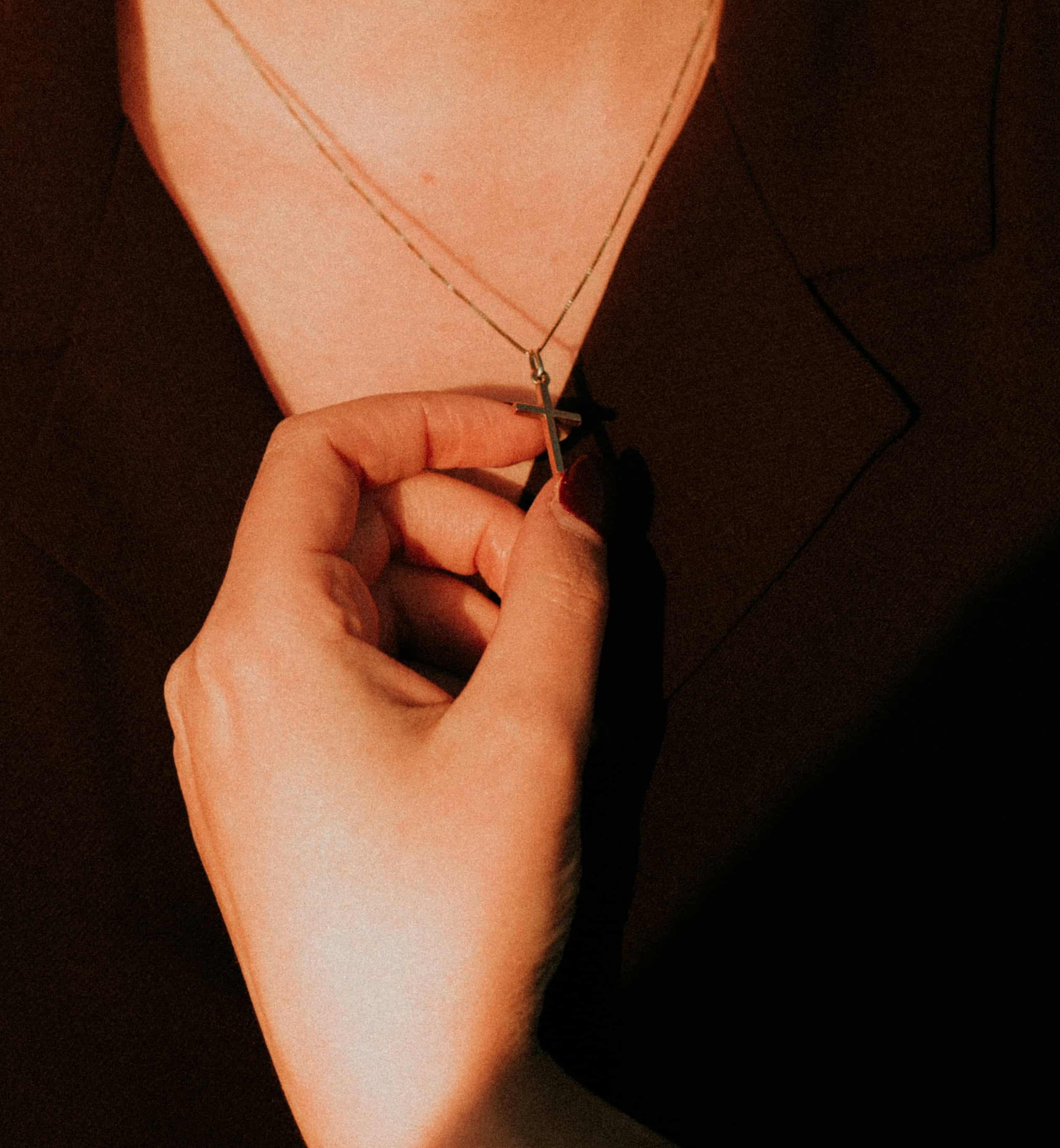 Persona sosteniendo un estuche con una cruz de oro, ideal para regalar joyería religiosa en ocasiones especiales y celebraciones